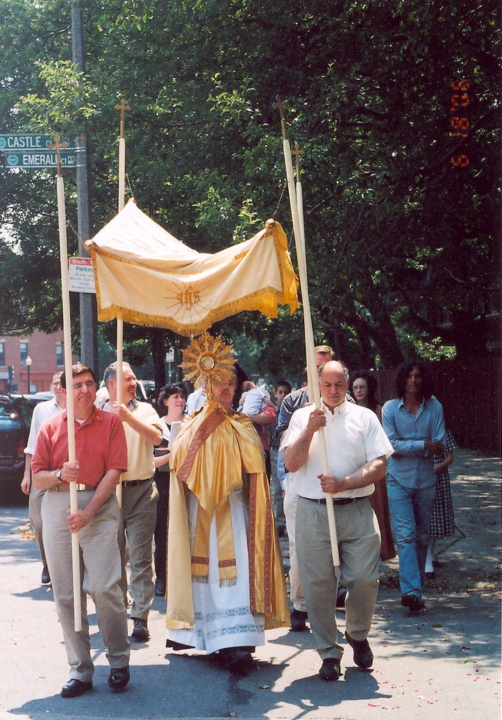 The canopy bearers shelter the Blessed Sacrament