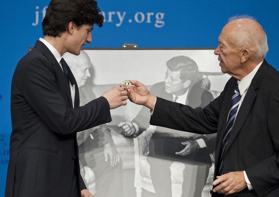 PHOTO: Jack  Schlossberg,  grandson of  President   Kennedy,   receives a   Russian coin  from Sergei  Krushchev, son  of Nikita  Krushchev,   Kennedy Library,  Boston, October  14th, 2012. 